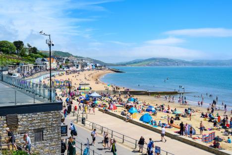 Crowded beach in Lyme Regis, Dorset, UK, on a sunny day.
