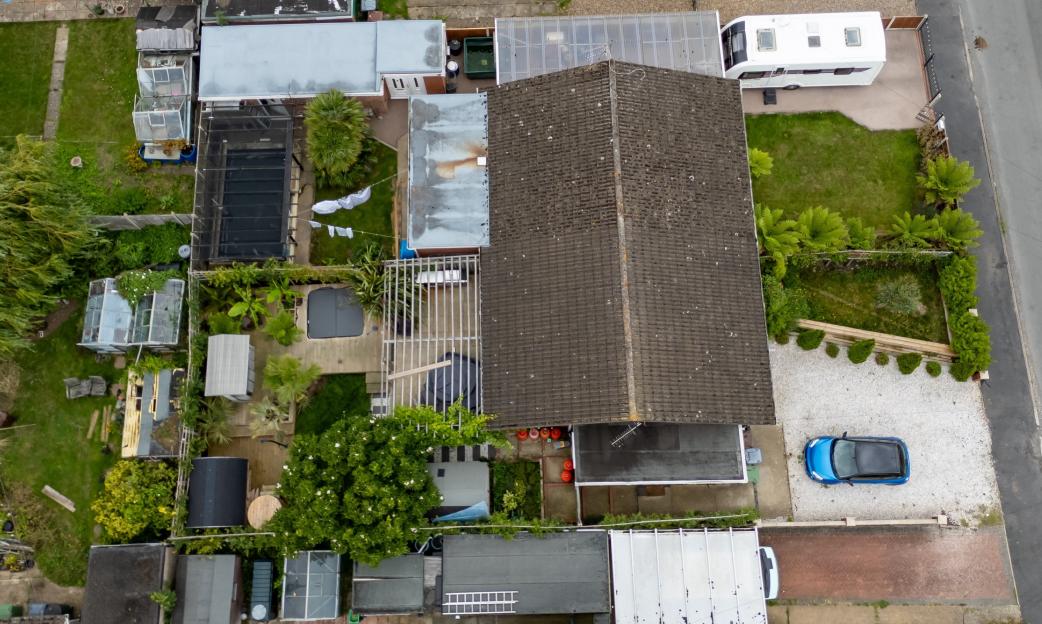 Aerial view of a bungalow and surrounding gardens.
