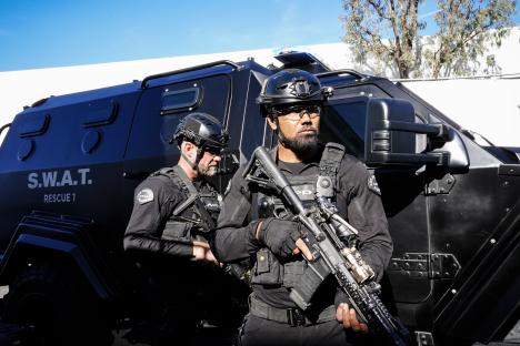 Two SWAT officers standing by a SWAT vehicle.