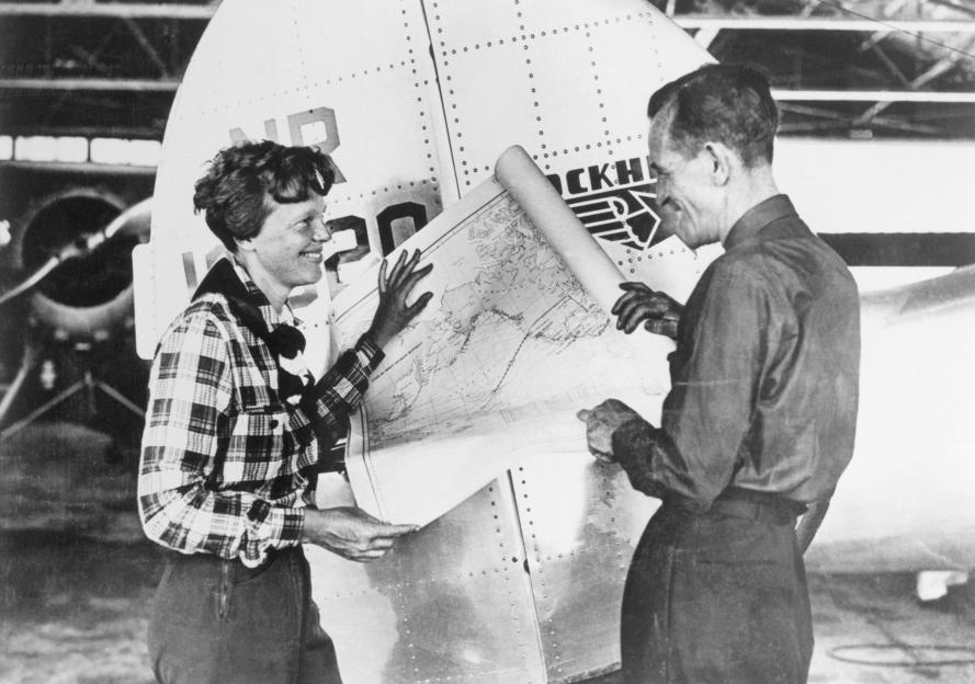 Amelia Earhart and Fred Noonan review a map of the Pacific showing their planned flight route.