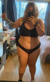 Woman taking a selfie in lingerie in her bedroom.