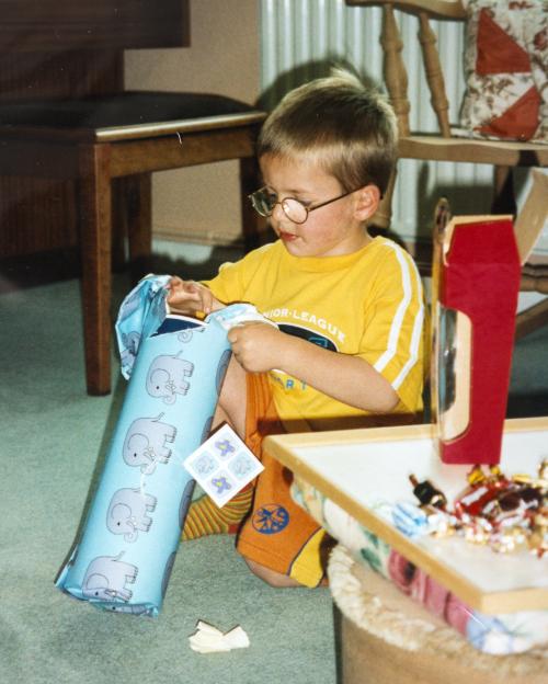 Andrew Gosden at age 5 unwrapping a gift.