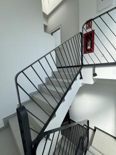 Interior view of a staircase with a black metal railing.