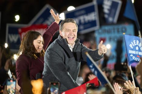 Pierre Poilievre giving a thumbs up at a campaign event with his wife.