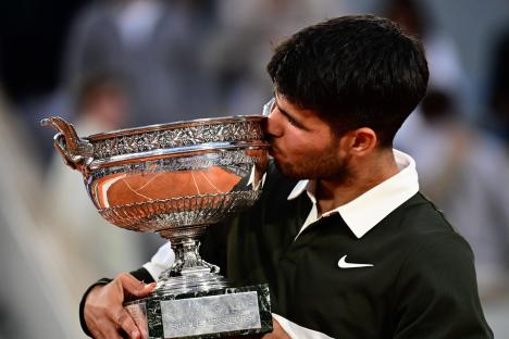 Carlos Alcaraz kissing the Roland Garros trophy.