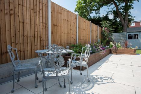 Sunny patio with gray metal furniture and a wooden fence.