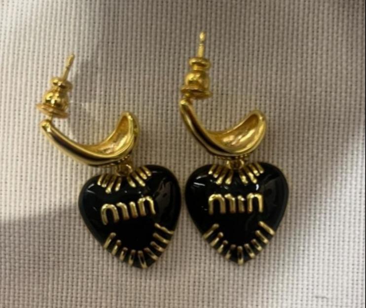 A pair of black, heart-shaped Miu Miu earrings with gold lettering.