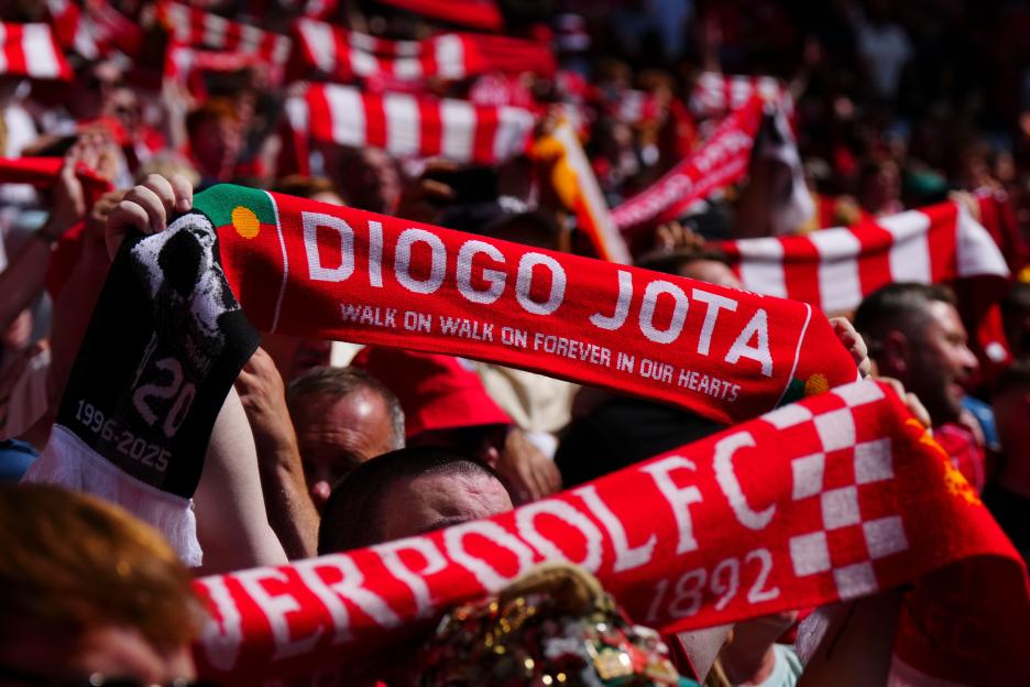 Liverpool fans holding scarves commemorating Diogo Jota.
