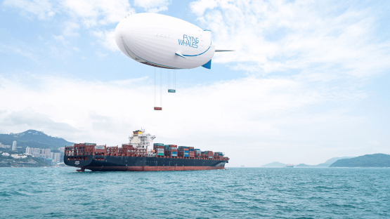 Flying Whales airship delivering cargo containers to a cargo ship at sea.