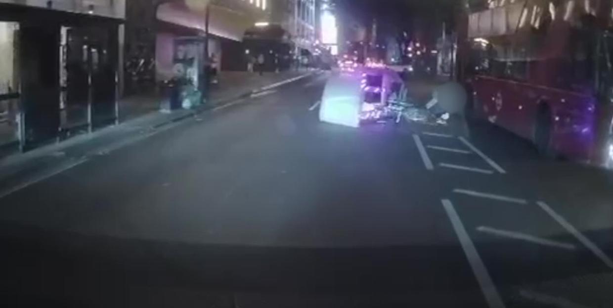 Nighttime street scene showing a car accident involving a cyclist and a bus.