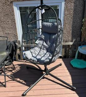 Black hanging egg chair on a deck.