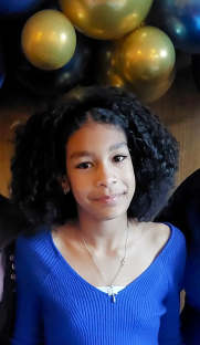 Portrait of a girl with curly hair wearing a blue sweater.