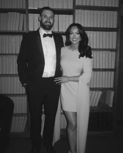 Black and white photo of a couple posing in front of bookshelves.