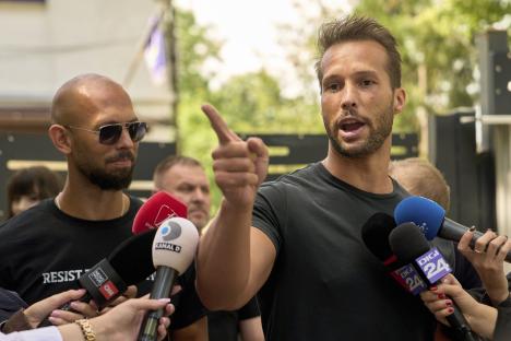 Andrew Tate speaking to reporters outside a police station.