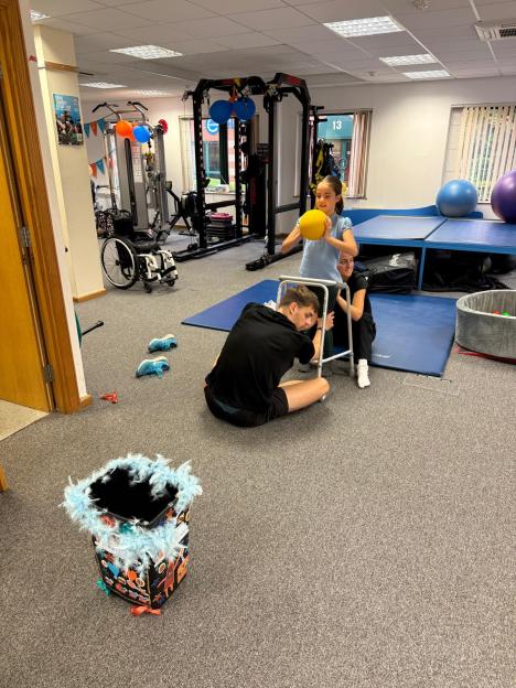 Ivy Amos, 9, with the assistance of two adults, practices walking with a frame in a physical therapy gym.