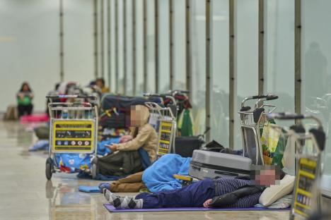 People sleeping on the floor of an airport terminal.
