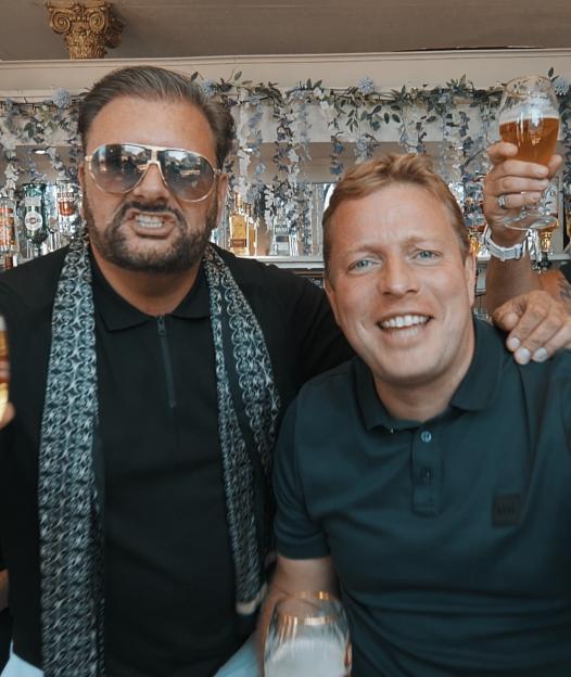 Robert Hisee wearing sunglasses and Tom Skinner smiling while holding beer glasses.