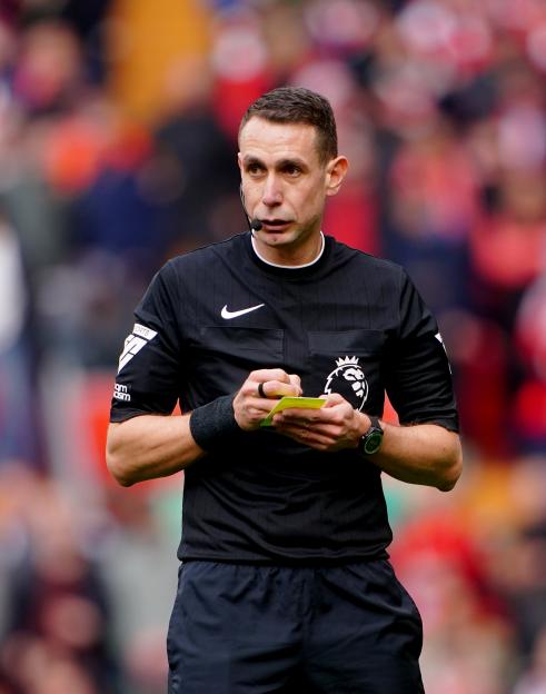 Photo of David Coote, a former Premier League referee, writing on a yellow card.