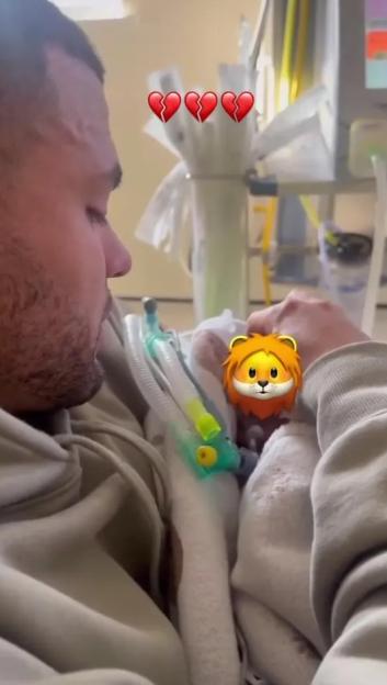 A grieving father holds his deceased infant son.