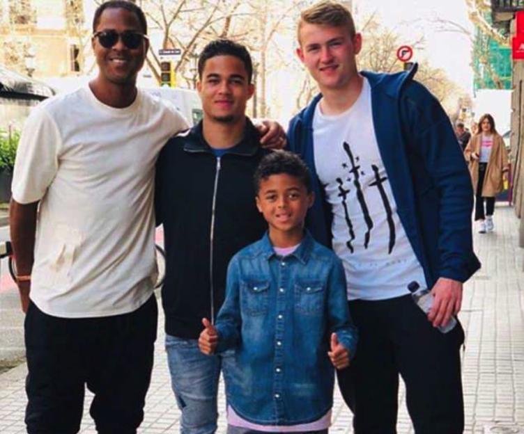 Four males of varying ages pose for a photo on a street.