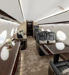 Interior of a private jet with seating and tables.