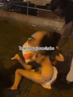 Two women fighting on a street at night.