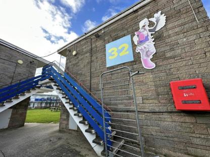 Building exterior with blue stairs, number 32, and a cartoon character.