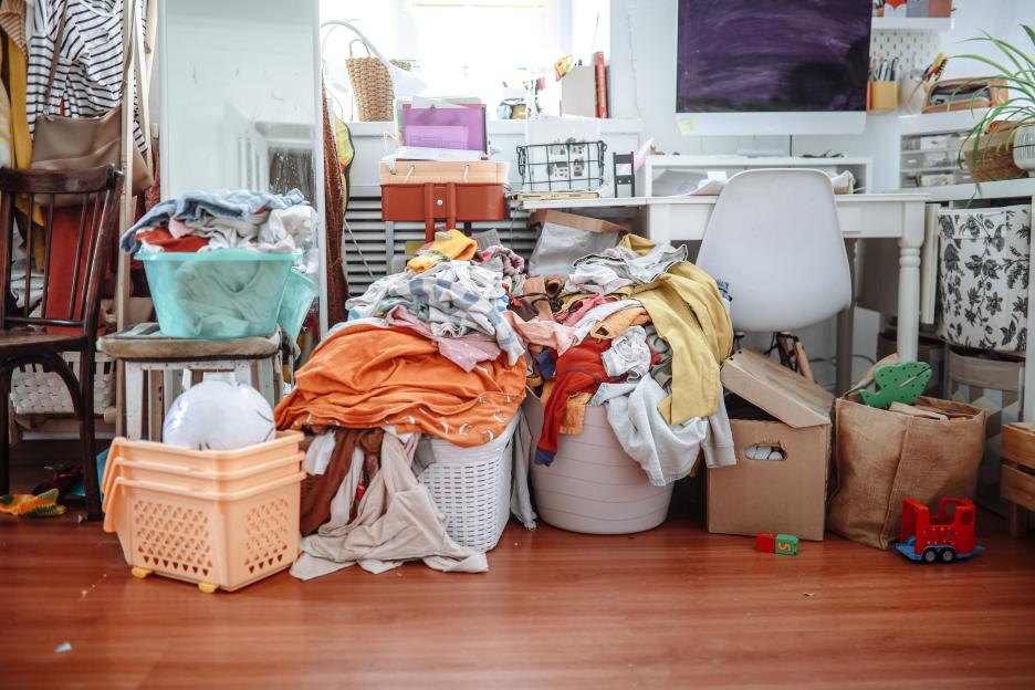 Household chaos: baskets of clean laundry and huge piles of clothes in cluttered living room