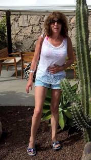 Woman standing near a cactus, holding her stomach.
