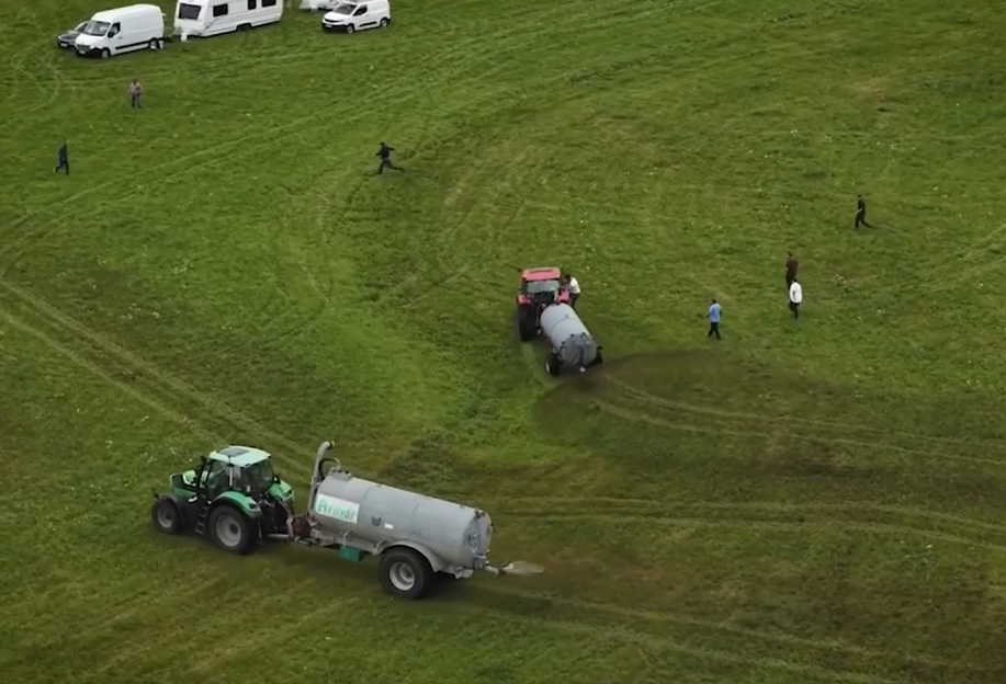 Aerial view of two tractors spreading fertilizer on a field.
