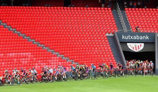 Cyclists at the start of a race in a stadium.