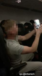 A partially obscured image of a passenger on an airplane.
