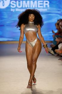 Megan Thee Stallion walking a runway in a silver swimsuit.