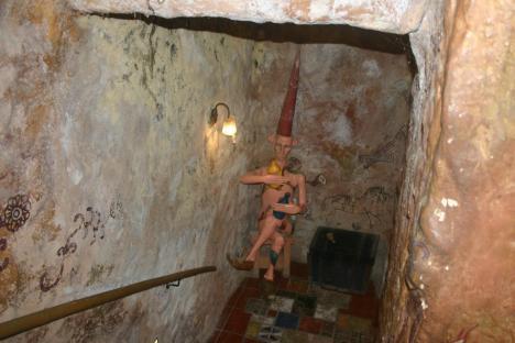 Statue of a figure holding vessels in a cave-like setting with wall art.