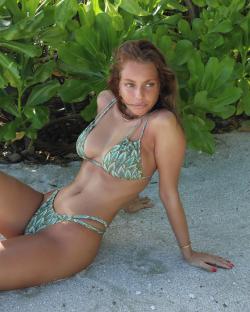 Woman in patterned bikini sitting on a beach.