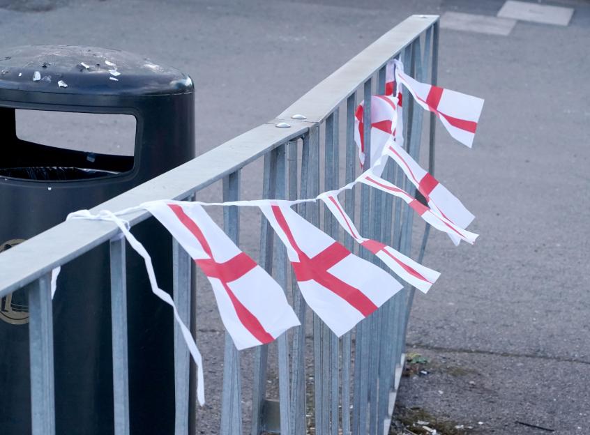 Small English flags strung on a metal fence.