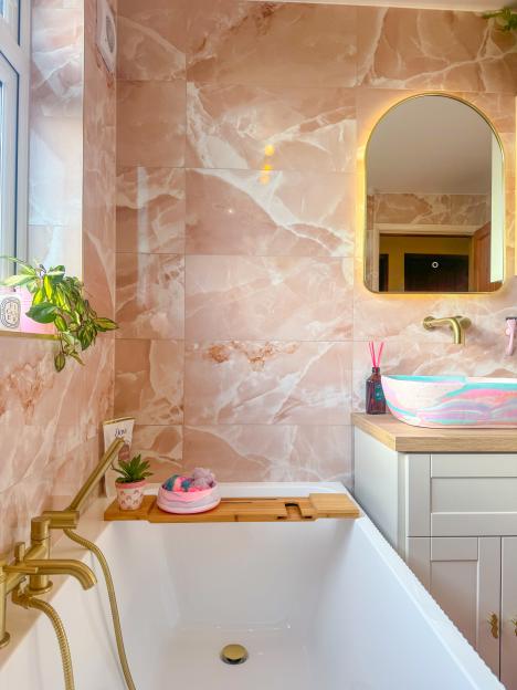 Pink marble-tiled bathroom with a free-standing bathtub and pastel sink.