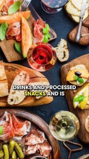 Overhead shot of various foods and drinks, including cured meats, fruit, bread, and wine.