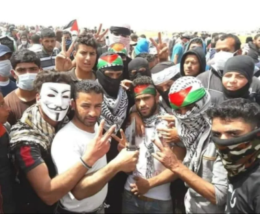 A group of people at a protest, some wearing masks and keffiyehs.