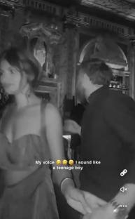 Screenshot of a black and white video showing two people holding hands in a dimly lit bar.