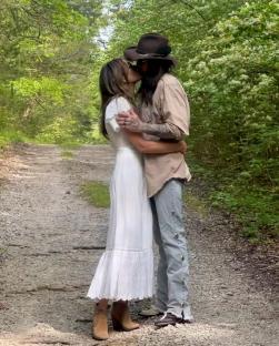A couple kissing on a dirt path.