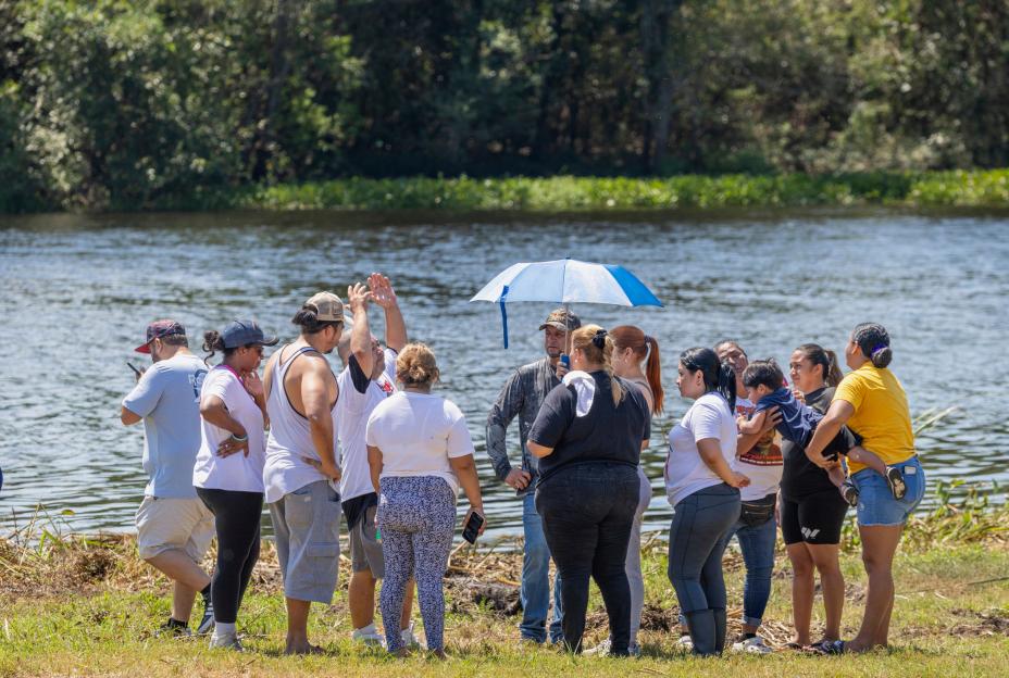 Friends and volunteers gather near a body of water.