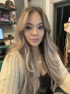 Woman with long blonde hair wearing a cream-colored cardigan.