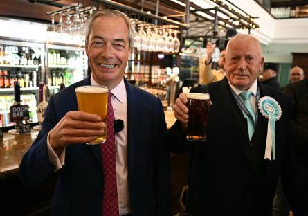 Nigel Farage and a Reform UK candidate holding pints of beer in a pub.