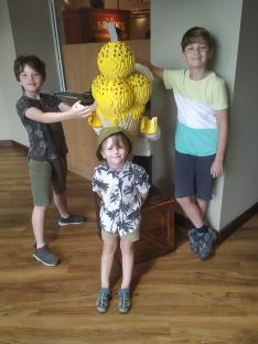 Three boys posing with a large Lego ice cream sculpture.