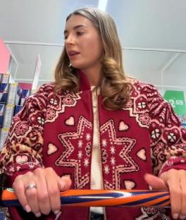 Woman in a red patterned sweater pushing a shopping cart.