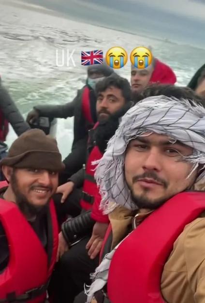 Several men wearing life jackets on a boat at sea, with text "UK" and a British flag emoji.
