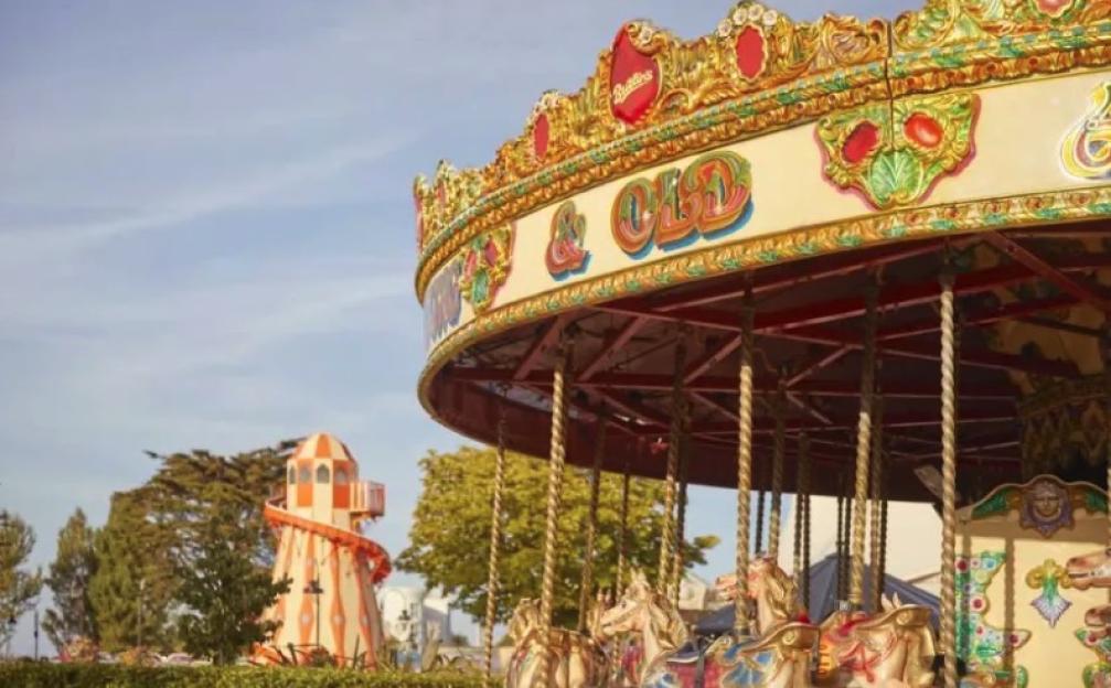 Carousel with painted horses and a smaller slide in the background.