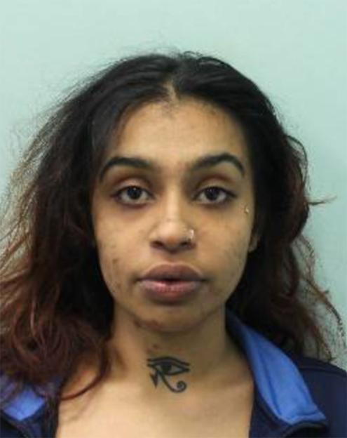Mugshot of Nazli Merthoca, a woman with dark hair, a nose ring, and an Eye of Horus tattoo on her throat.