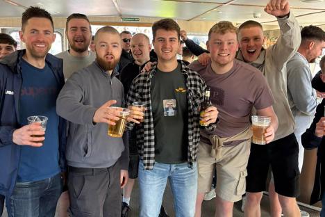 Group of men on a boat party holding drinks.
